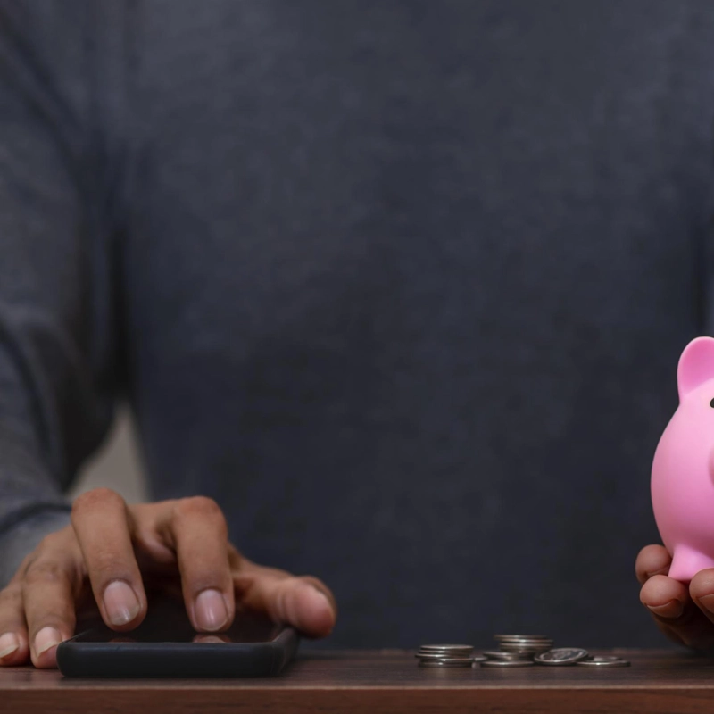 Person mit Smartphone und Sparschwein.
